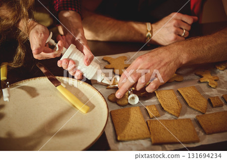 Family And Friends Glaze Cookies With Icing During Cozy Baking Night, Decorating Gingerbread Shapes On The Table 131694234