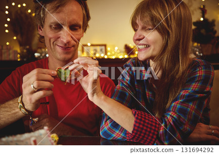 Couple Share Heart-Shaped Cookie During Cozy Christmas Evening Couple Share Heart-Shaped Cookie During Cozy Christmas Evening 131694292