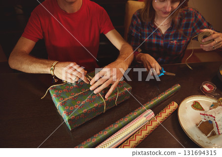 Family And Friends Gift Wrapping: Couple Wrapping Presents At Home With Paper, Tape, And Scissors Family And Friends Gift Wrapping: Couple Wrapping Presents At Home With Paper, Tape, And Scissors 131694315