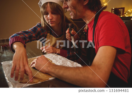 Two People Baking Together At Home: Woman In Apron And Man With Knife Rolling Dough For Pastry Two People Baking Together At Home: Woman In Apron And Man With Knife Rolling Dough For Pastry 131694481
