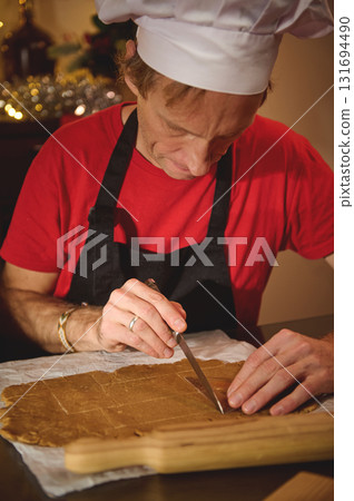 Chef In White Hat Slices Dough On Parchment In Cozy Kitchen With Red Shirt And Black Apron, Showcasing Baking Skill And Culinary Craft In A Warm Studio Setting 131694490