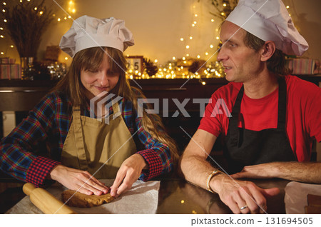 Family Friends Baking Cookies Together in Cozy Kitchen with Chef Hats and Warm Holiday Lights 131694505