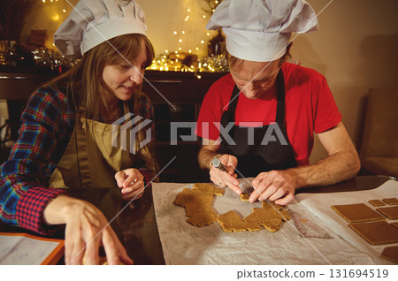 Family And Friends In Chef Hats Bake Gingerbread Cookies Together In A Cozy Kitchen 131694519