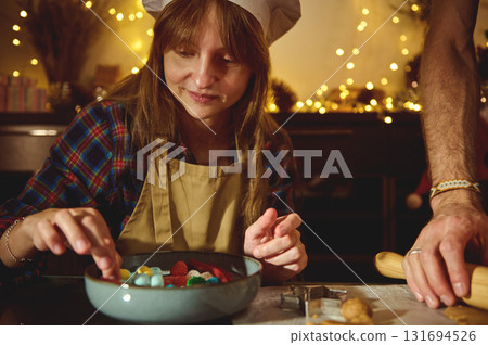 Young Woman Chef In Apron And Hat Decorates Colorful Candies In Cozy Holiday Kitchen 131694526