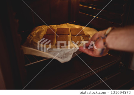 Warm Oven Cookies On A Tray: Hand Places Golden Rectangular Cookies Into The Oven 131694573