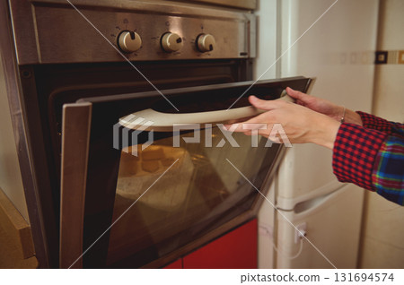 Person Opens Oven In Cozy Kitchen With Plaid Shirt Sleeves Preparing Food, Warm Lighting, Home Cooking Moment, Family Home, Everyday Baking Scene Person Opens Oven In Cozy Kitchen With Plaid Shirt Sleeves Preparing Food, Warm Lighting, Home Cooking Moment, Family Home, Everyday Baking Scene 131694574