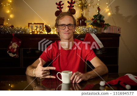 Festive Selfie With Reindeer Antlers: Man In Red Shirt At Holiday Home, Cozy Christmas Lights And Coffee Mug Setting 131694577