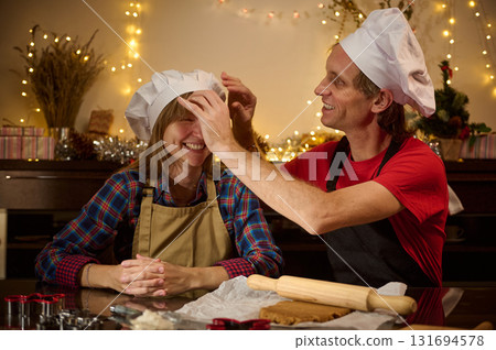 Happy Couple Cooking Together With Chef Hats During Festive Christmas Decor 131694578