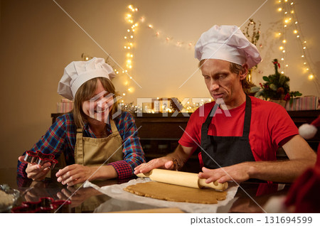 Family Chefs Roll Dough and Bake Cookies in Festive Kitchen Under Christmas Lights Family Chefs Roll Dough and Bake Cookies in Festive Kitchen Under Christmas Lights 131694599