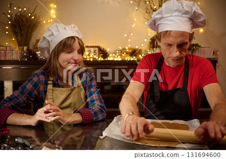 Bakers in Chef Hats Rolling Dough Together in a Cozy Kitchen 131694600