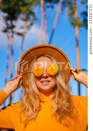 Woman faceless yellow sweater closing eyes with orange dahlia into camera Autumn Fall Bouquet for Thanksgiving holiday. Seasonal Warm colorful blossom flowers arrangement festive decoration 131697331