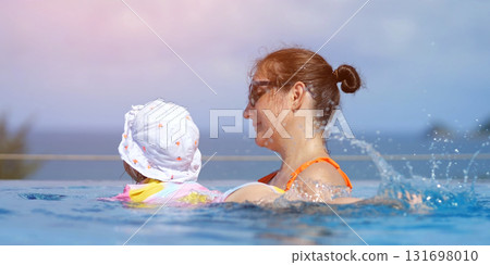 Mother and daughter swimming in infinity pool Mother and daughter swimming in infinity pool 131698010
