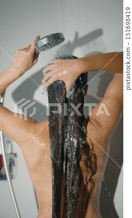 A woman showers with her long hair flowing, enjoying a refreshing moment of beauty and care 131698419