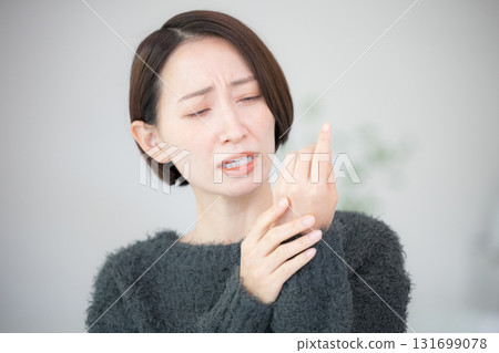 一位女士在手上塗抹乳霜並進行護理——她因手部粗糙而煩惱 一位女士在手上塗抹乳霜並進行護理——她因手部粗糙而煩惱 131699078