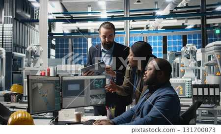 Group of professional consultants reviewing data and checklists in a high tech solar panel plant, ensuring manufacturing process meets sustainable energy and innovation standards. Camera A. Group of professional consultants reviewing data and checklists in a high tech solar panel plant, ensuring manufacturing process meets sustainable energy and innovation standards. Camera A. 131700073
