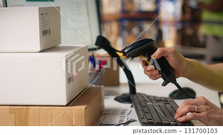 Asian male staff uses handheld scanner to register airway bill information, updating the package tracking software in real time with barcode reader and shipment details. Stock room. Camera B. 131700103