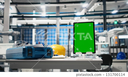 Empty engineering desk in a solar power manufacturing plant with green screen, industrial workspace surrounded by robotic arms and solar panel assembly lines. Monitoring performance. Empty engineering desk in a solar power manufacturing plant with green screen, industrial workspace surrounded by robotic arms and solar panel assembly lines. Monitoring performance. 131700114