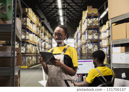Warehouse operations staff reviewing package dispatch details, order processing for cargo and inventory organization. Handling shipment records used in daily logistics center activities. 131700187
