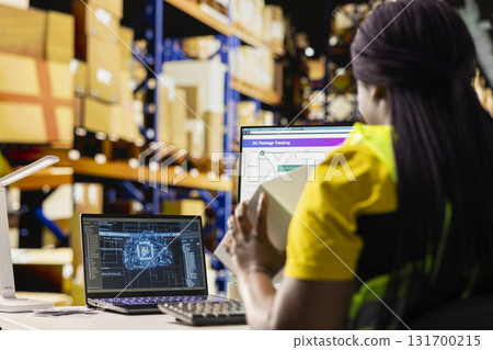 Black warehouse clerk managing orders in boxes next to AI machine learning, working on e-commerce with help from artificial intelligence neural networks. Fulfillment center tasks. Black warehouse clerk managing orders in boxes next to AI machine learning, working on e-commerce with help from artificial intelligence neural networks. Fulfillment center tasks. 131700215