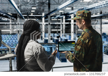 Army soldiers in data center training artificial intelligence to prioritize critical enemy targets. Military units in server room look at AI locking mechanism confirming hostile presence on screen Army soldiers in data center training artificial intelligence to prioritize critical enemy targets. Military units in server room look at AI locking mechanism confirming hostile presence on screen 131700237