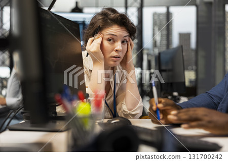 Concerned woman working with a colleague in a stressful situation, struggling to meet project deadline and feeling exasperated with the overwhelming tasks. Tension at the job. 131700242