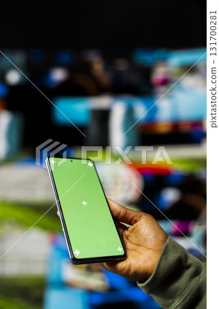 Close up of woman using mockup smartphone to enjoy freedom of unlimited video content in metaverse. Person uses green screen phone to look at online video channels, isolated over digital wall backdrop Close up of woman using mockup smartphone to enjoy freedom of unlimited video content in metaverse. Person uses green screen phone to look at online video channels, isolated over digital wall backdrop 131700281