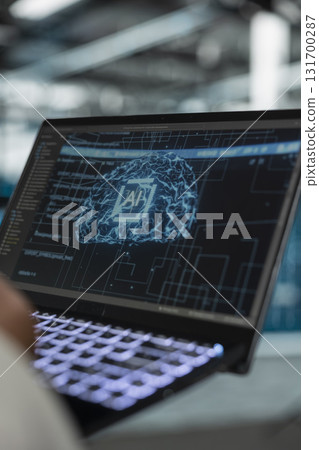 Close up of data center software developer using artificial intelligence computerized model on laptop to oversee operations. Server room IT expert working with AI neural networks algorithms on device 131700287