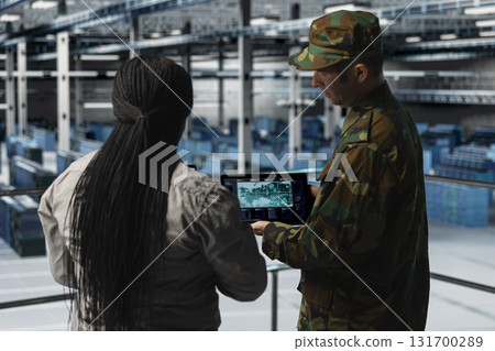IT specialist briefing commander in army server hub using tactical interface on notebook. Military officer in data center and engineer monitoring warfare drone telemetry on laptop IT specialist briefing commander in army server hub using tactical interface on notebook. Military officer in data center and engineer monitoring warfare drone telemetry on laptop 131700289