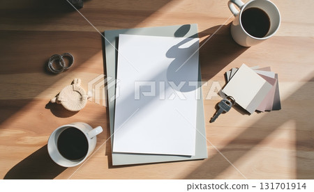 Cozy Workspace with Blank Papers, Coffee Cups, Keys, Color Swatches and Natural Light Shadows 131701914