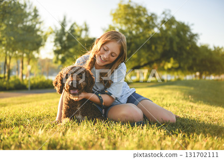 Portrait of one brown portuguese water dog outdoors on grass with little child girl 131702111