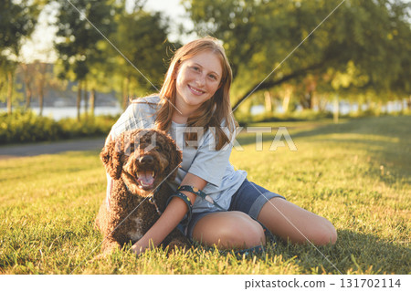 Portrait of one brown portuguese water dog outdoors on grass with little child girl Portrait of one brown portuguese water dog outdoors on grass with little child girl 131702114