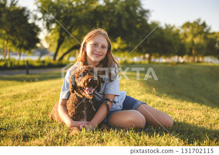 Portrait of one brown portuguese water dog outdoors on grass with little child girl Portrait of one brown portuguese water dog outdoors on grass with little child girl 131702115