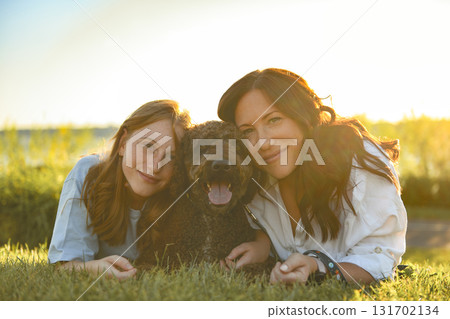 brown portuguese water dog outdoors on grass with mother and daughter brown portuguese water dog outdoors on grass with mother and daughter 131702134