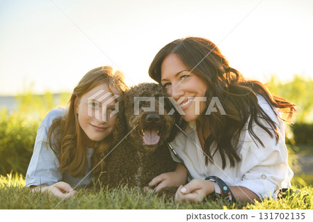 brown portuguese water dog outdoors on grass with mother and daughter brown portuguese water dog outdoors on grass with mother and daughter 131702135