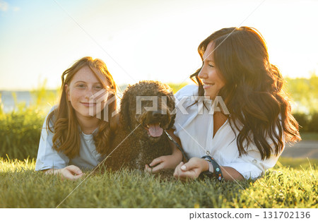 brown portuguese water dog outdoors on grass with mother and daughter brown portuguese water dog outdoors on grass with mother and daughter 131702136