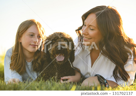 brown portuguese water dog outdoors on grass with mother and daughter brown portuguese water dog outdoors on grass with mother and daughter 131702137