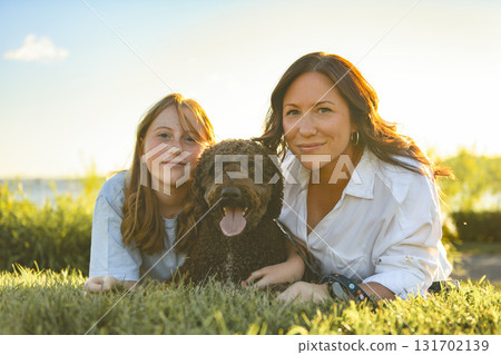 brown portuguese water dog outdoors on grass with mother and daughter 131702139
