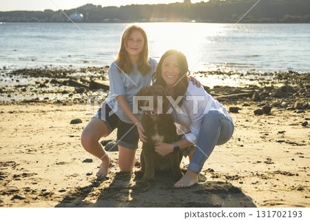 brown portuguese water dog outdoors on the beach with mother and daughter brown portuguese water dog outdoors on the beach with mother and daughter 131702193