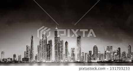 Urban city skyline with illuminated skyscrapers and waterfront railing in black and white at night, Dubai Marina bay UAE Urban city skyline with illuminated skyscrapers and waterfront railing in black and white at night, Dubai Marina bay UAE 131703233