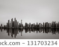 Monochrome city skyline with tall skyscrapers reflecting on calm water under a cloudy sky, Dubai Marina bay UAE 131703234