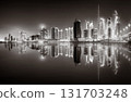 Urban city skyline with illuminated skyscrapers and waterfront railing in black and white at night, Dubai Marina bay UAE 131703248