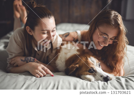 Happy couple cuddling on their bed at home with dog Happy couple cuddling on their bed at home with dog 131703621