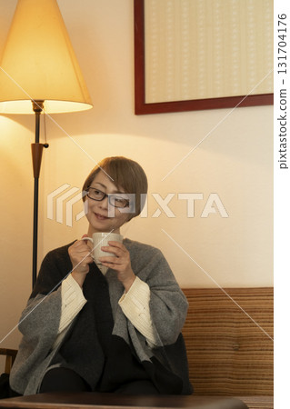 一位老年婦女在客廳喝著熱氣騰騰的飲料 131704176