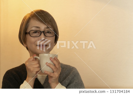 一位老年婦女在客廳喝著熱氣騰騰的飲料 131704184