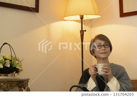 一位老年婦女在客廳喝著熱氣騰騰的飲料 131704203