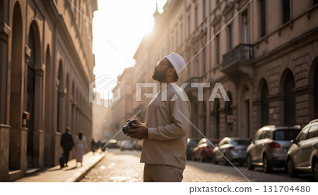 Person in Traditional Attire Holding Camera on Street During Golden Hour with Soft Sunlight 131704480