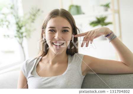 Cheerful relaxed young woman with wireless earbud resting on sofa Cheerful relaxed young woman with wireless earbud resting on sofa 131704802