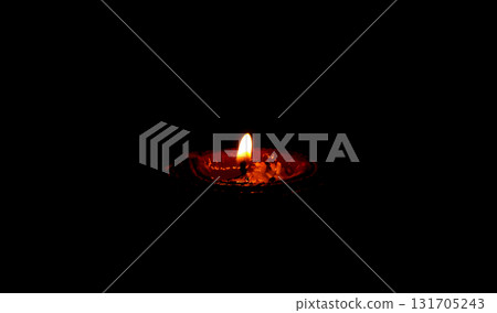 Burning Clay Oil Lamp in Darkness Symbolizing Light and Hope 131705243