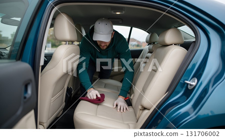 Person Cleaning Car Interior with Cloth and Wearing Cap in a Sedan Vehicle 131706002