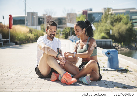 Young fitness couple sporty sit and watching watch on a city on summer day 131706499
